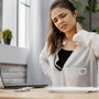 mujer con dolor de cuello sentada frente al computador